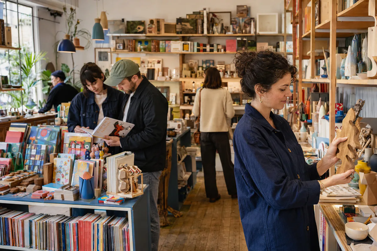 People discovering books, design-led toys, stationery, ceramics and cultural objects in a lively independent concept store.
